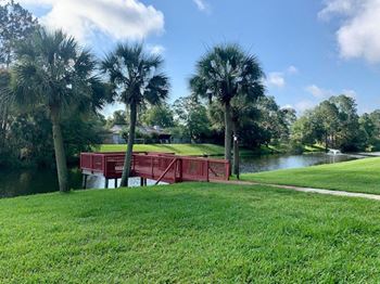 a red bridge over a body of water with palm trees at Timberwalk at Mandarin, Jacksonville, FL, 32257